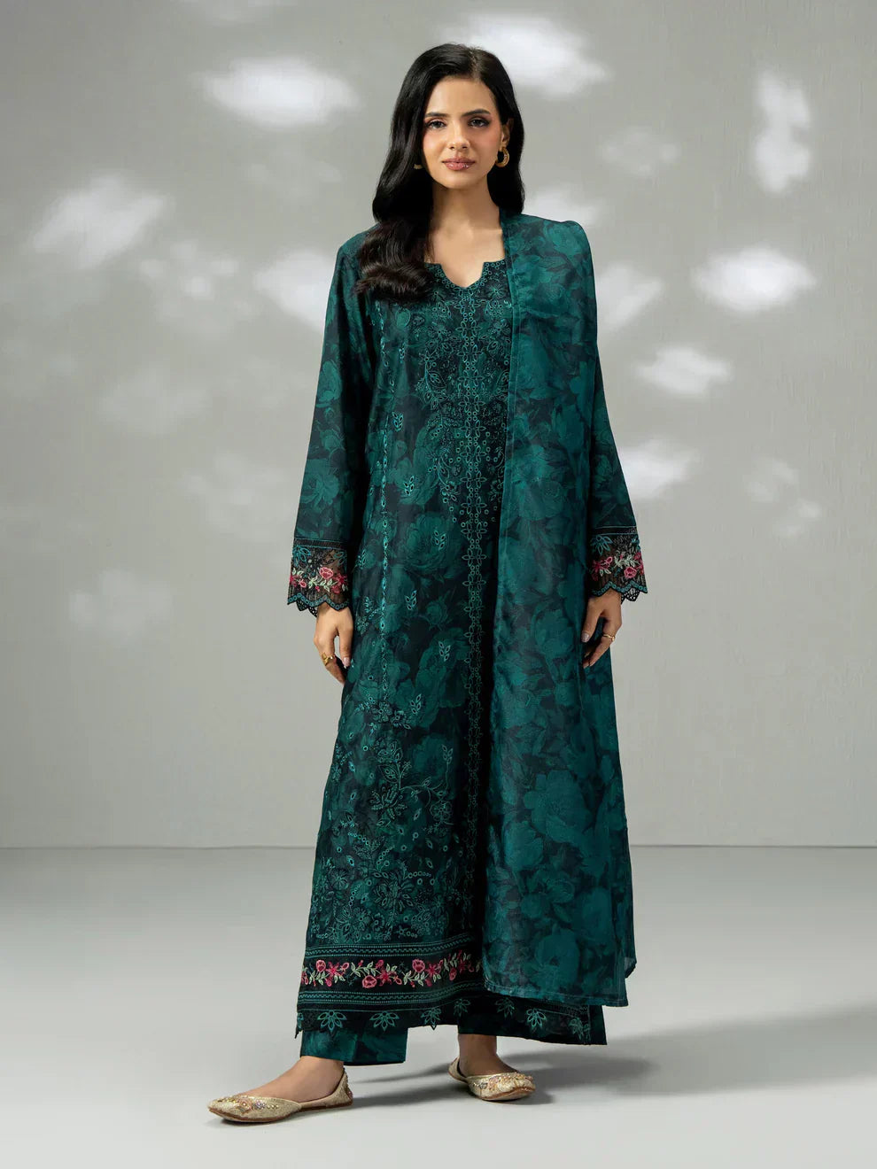  A stylish Pakistani designer lawn suit worn in a modern UK garden setting, blending traditional embroidery with contemporary fashion.
