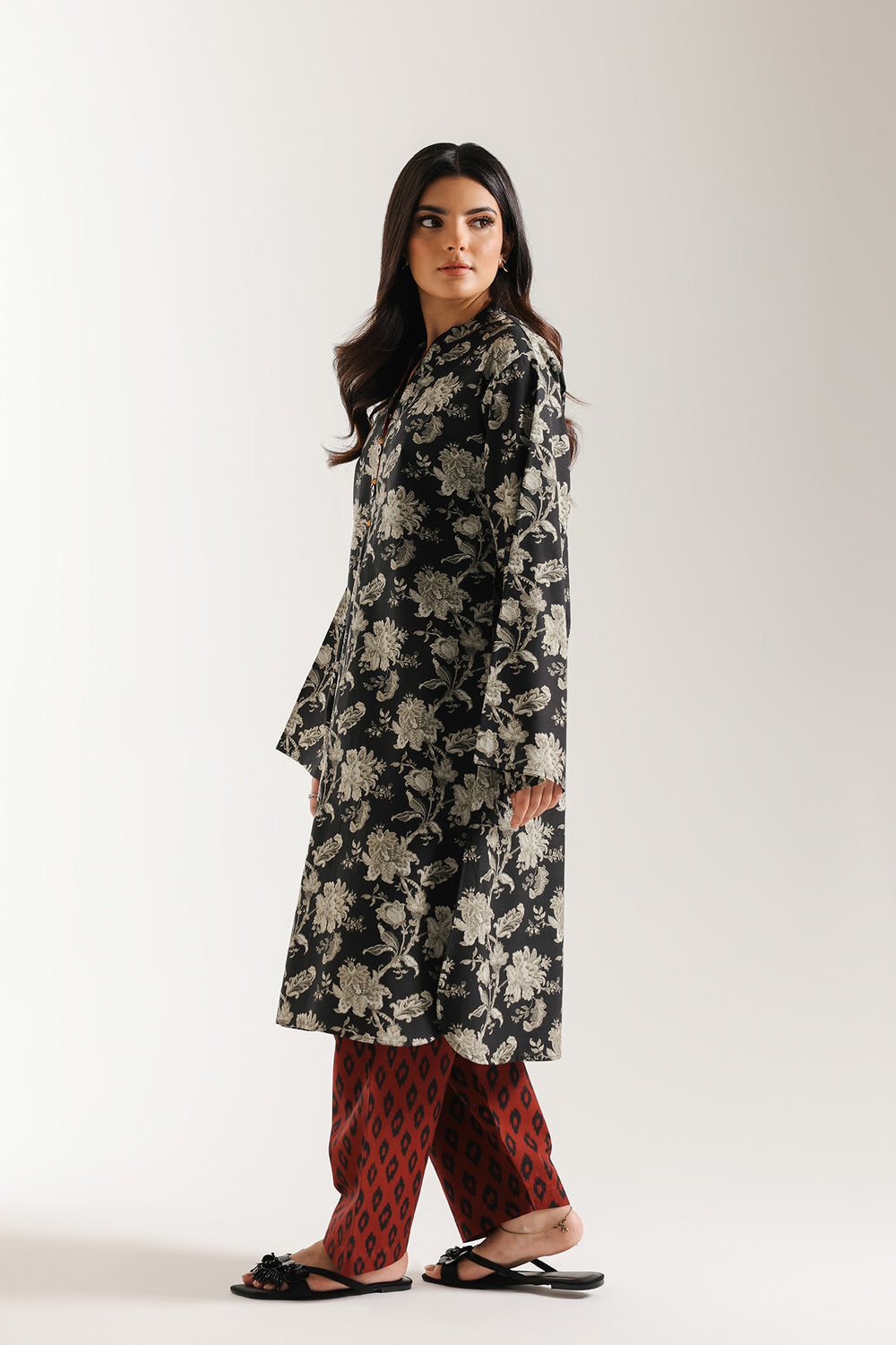 Woman wearing ethnic black floral dress with red shalwar on a white background
