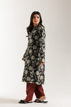Woman wearing ethnic black floral dress with red shalwar on a white background