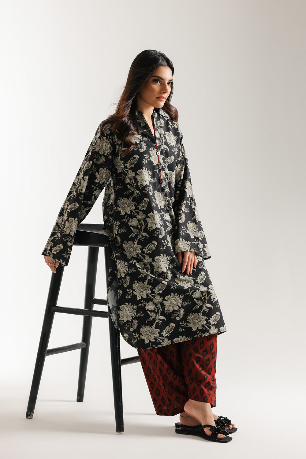 Woman wearing ethnic -black floral dress with red shalwar on a white background