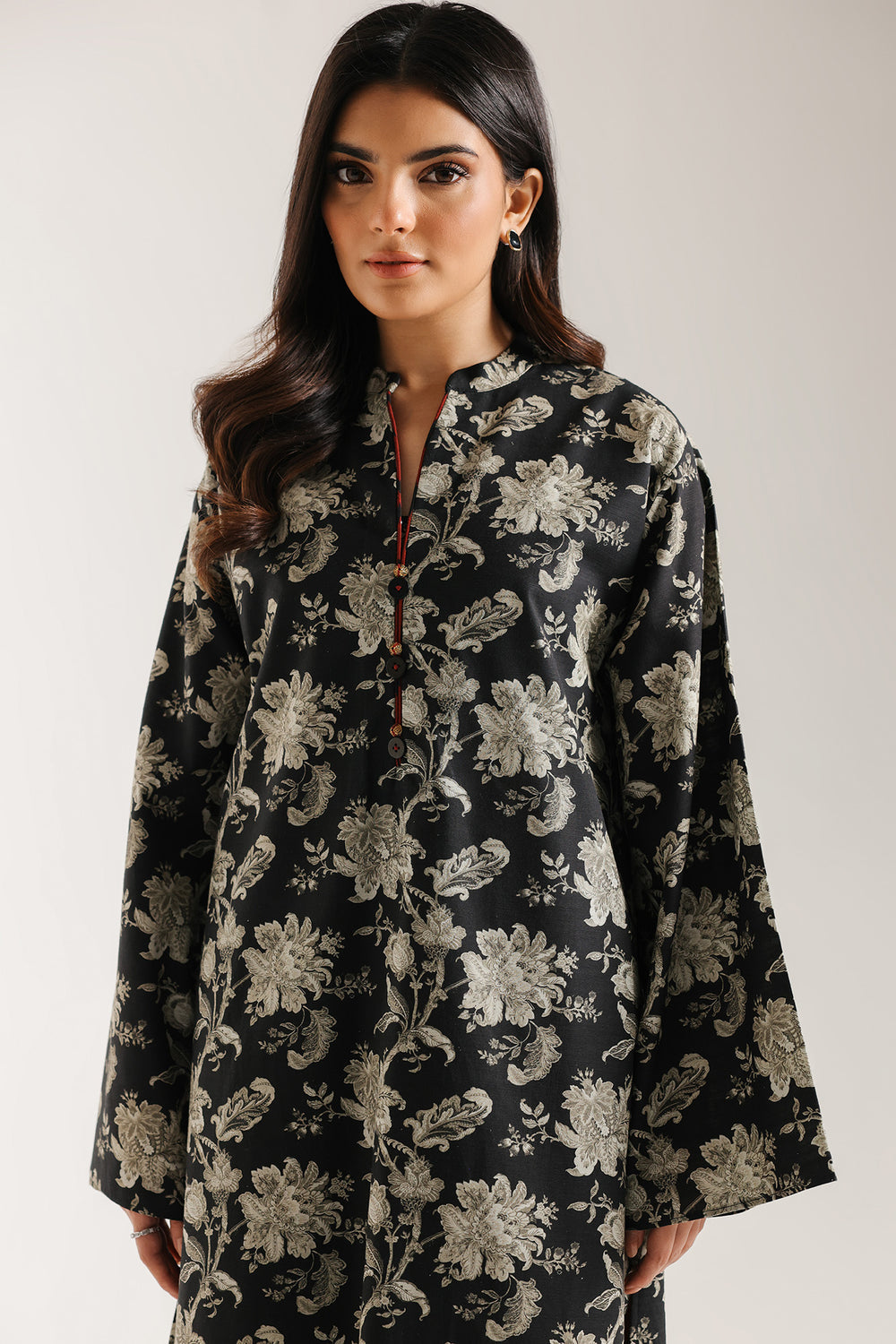 Woman wearing ethnic pakistani black floral patterned dress against a white background