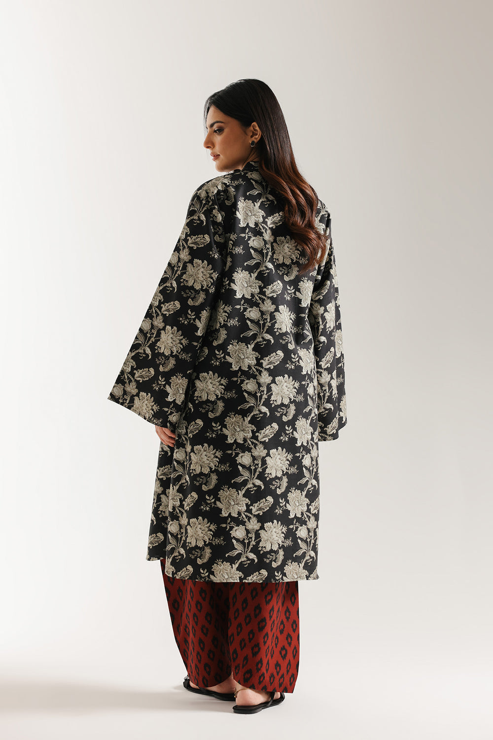 Woman wearing a black ethnic floral kimono-style outfit on a white background
