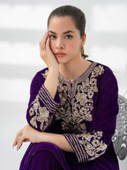Woman wearing a purple outfit with intricate gold embroidery against a neutral background