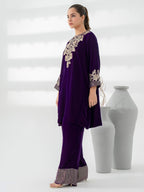 Woman wearing a purple outfit with intricate gold embroidery standing next to white vases on a light gray background