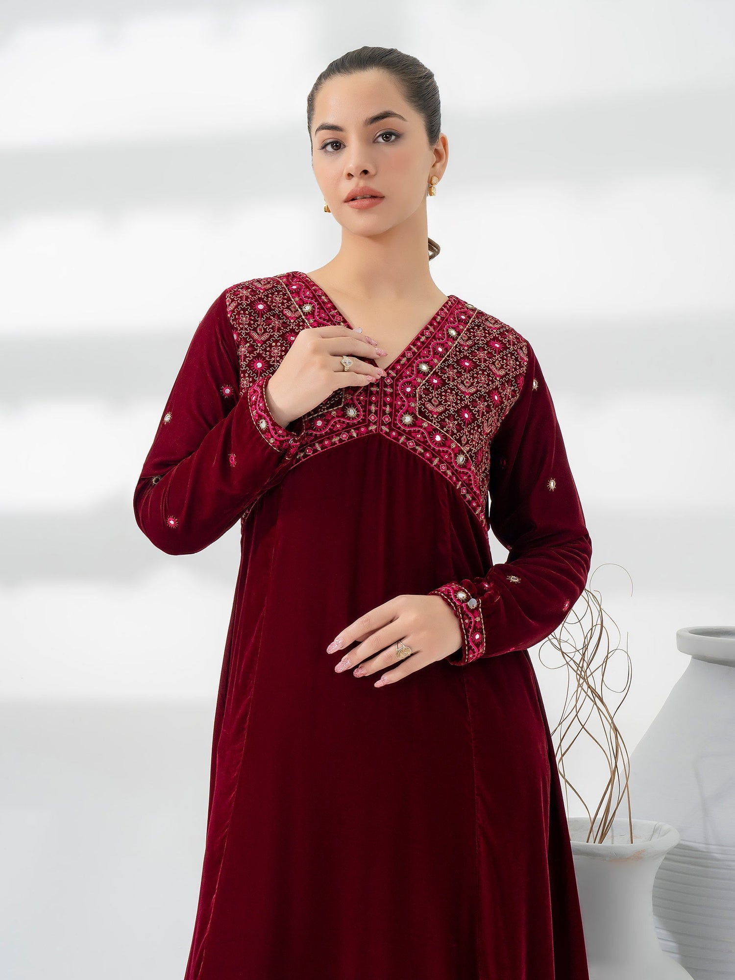 Woman wearing a maroon limelight velvet dress with intricate patterns on a white background