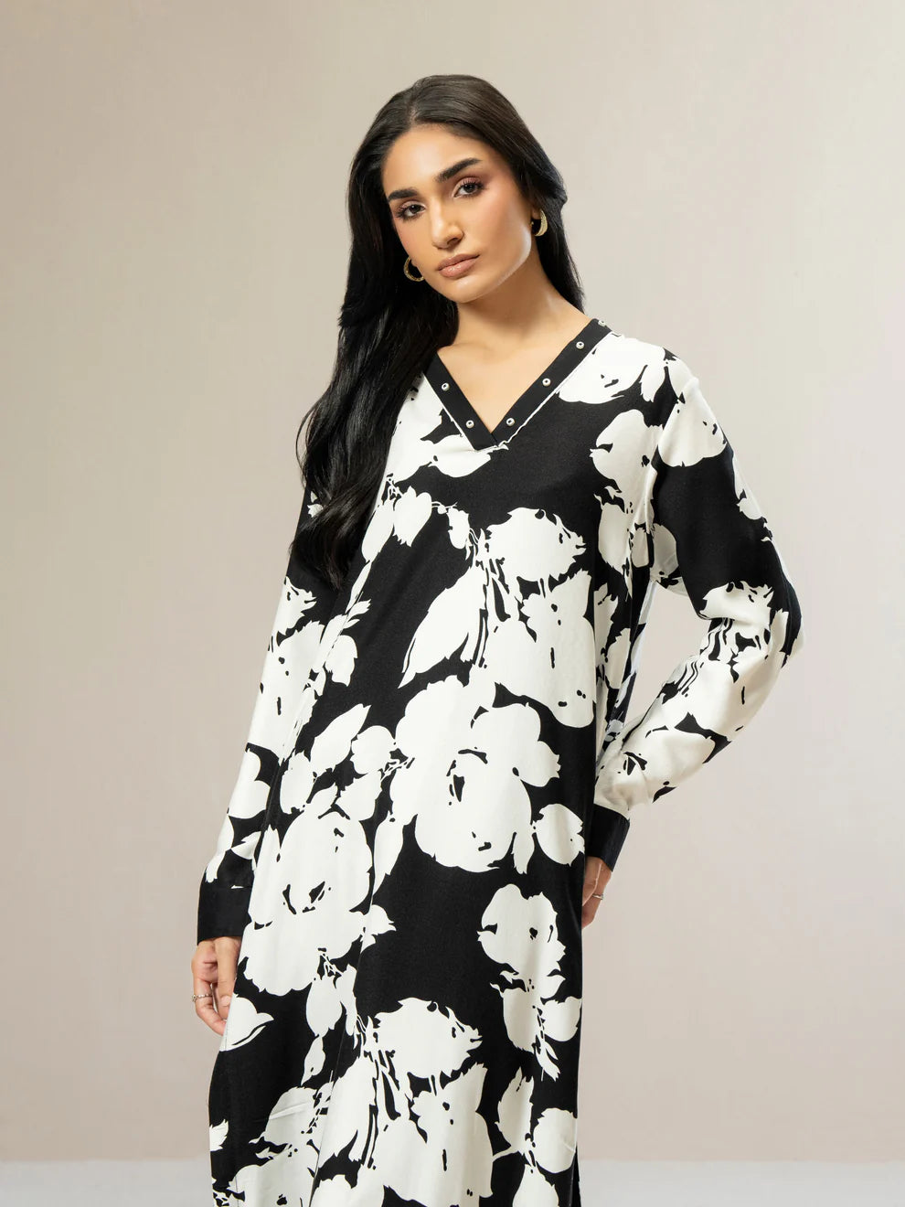 Woman wearing a black and white floral dress against a beige background