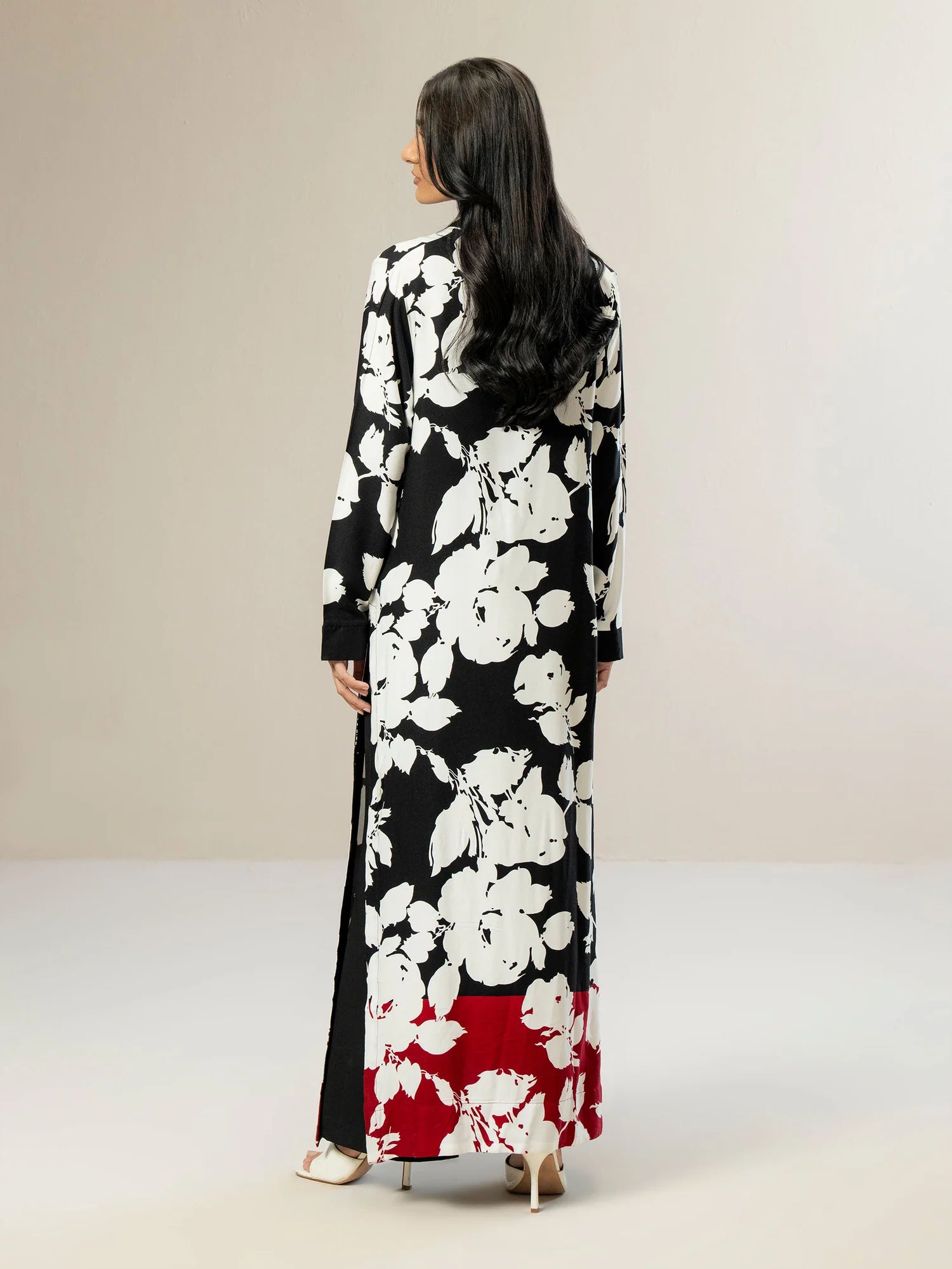 Woman wearing a black floral dress with a red bottom section on a plain background