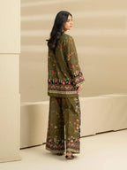 Woman wearing a green traditional outfit with floral patterns in a minimalistic setting