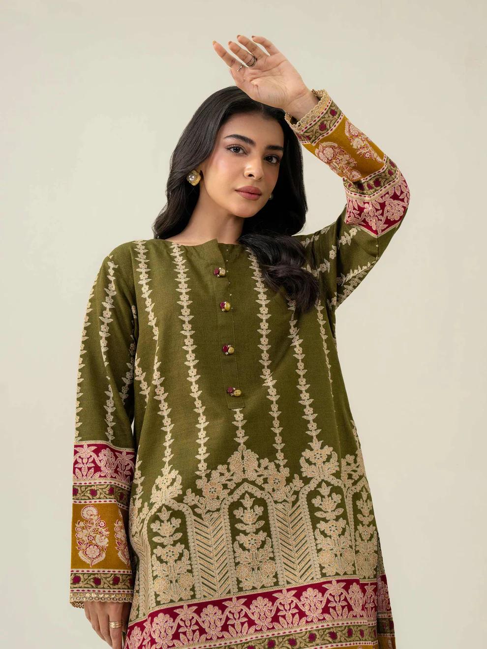 Woman wearing a green embroidered traditional outfit with a plain background