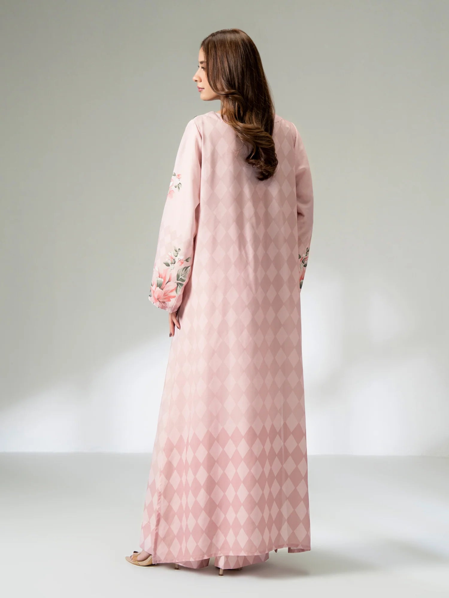 Woman wearing a pink dress with floral embroidery on a white background