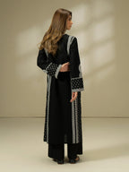 Woman wearing a black dress with white patterns on a beige background