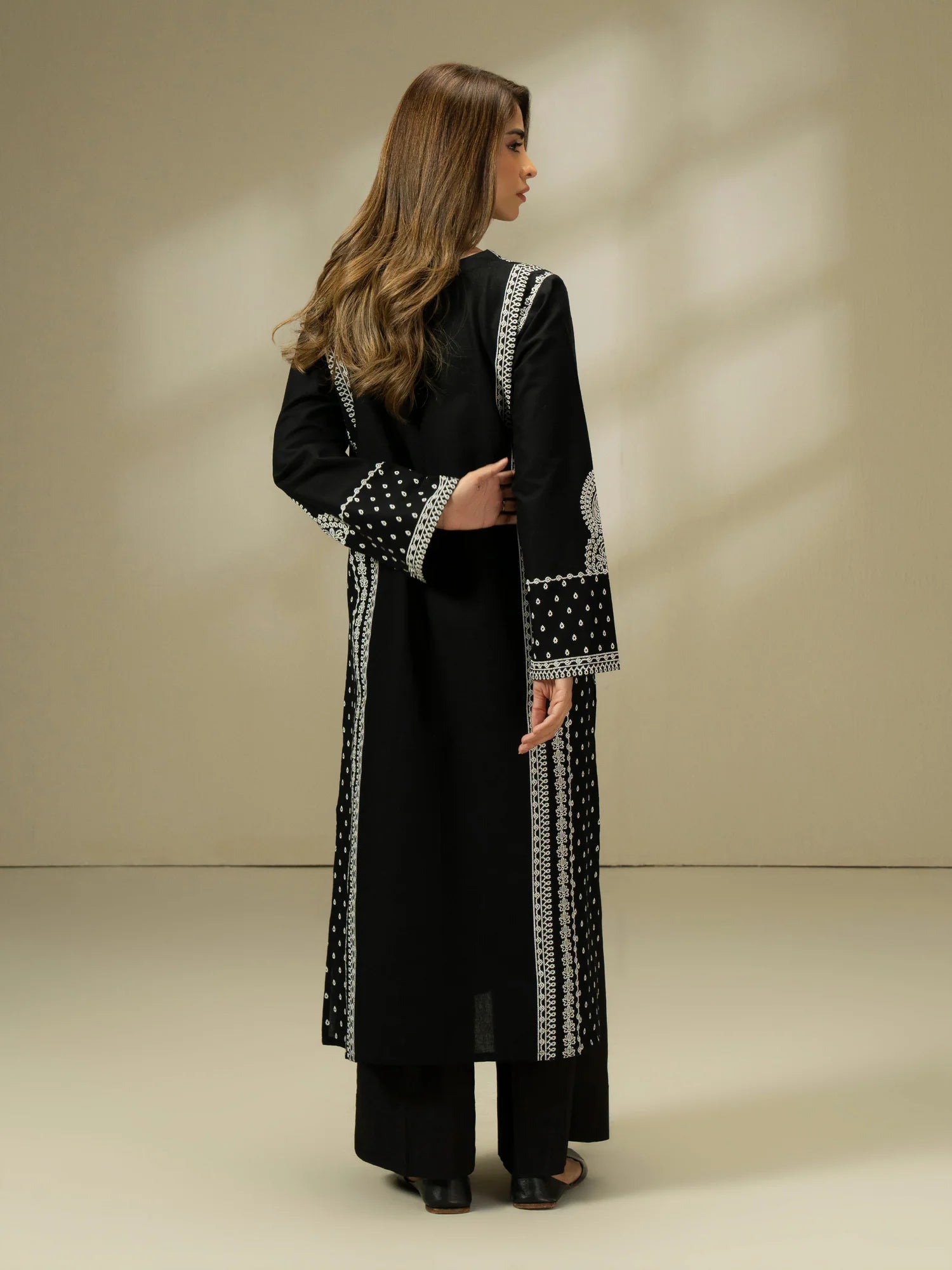 Woman wearing a black dress with white patterns on a beige background
