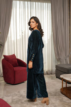 Woman in a blue velvet outfit standing in a modern living room.