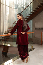 Woman in a burgundy outfit standing in a modern interior setting with a staircase.