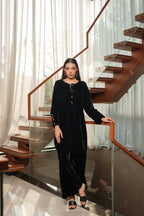 Woman in a black outfit standing on a modern staircase with glass railings.